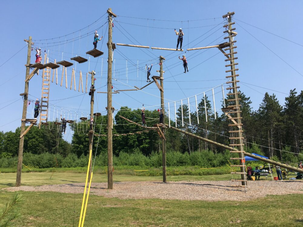 Photo of a group of people on both the first and second level of the adventure course