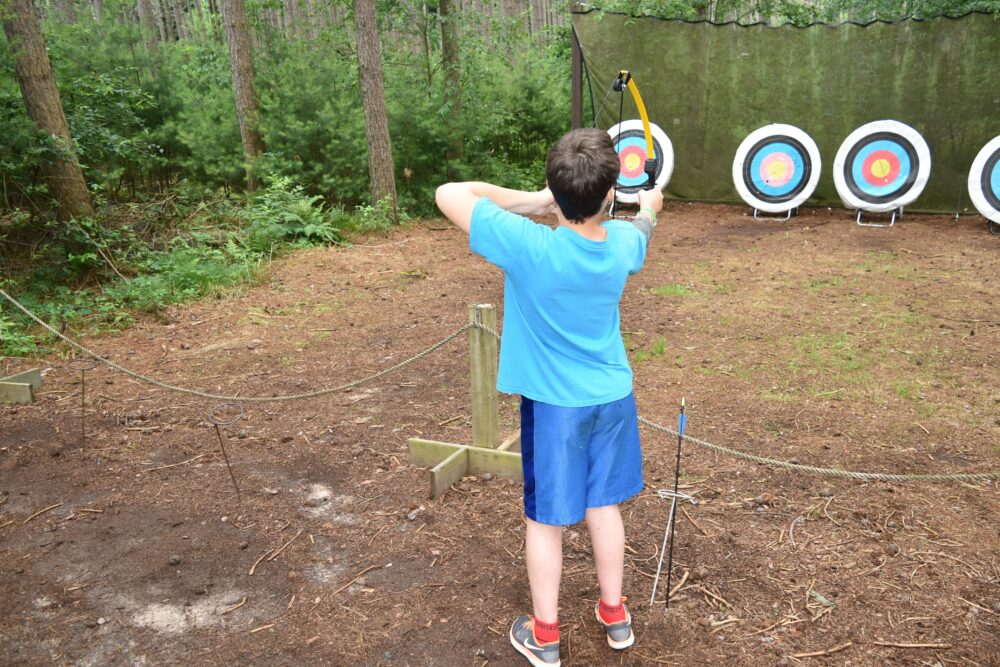 Photo of a child pulling back a bow for archery