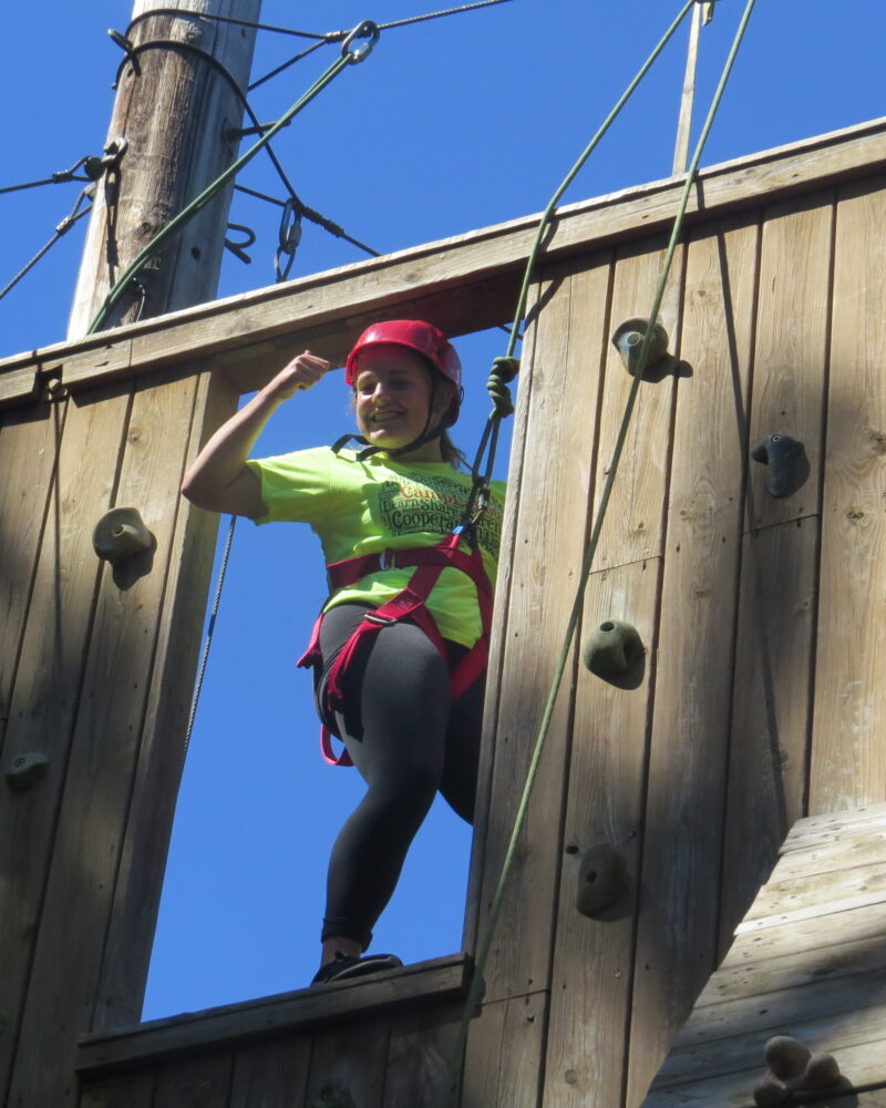 Photo of an individual standing at the top of the climbing tower flexing their arm