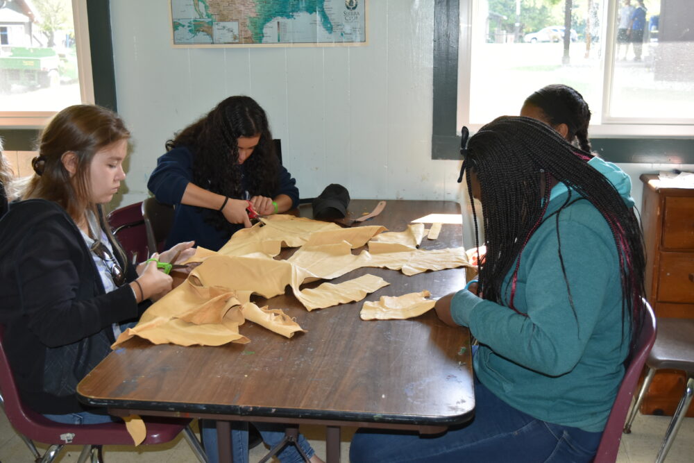 Photo of a group of campers cutting leather in crafts