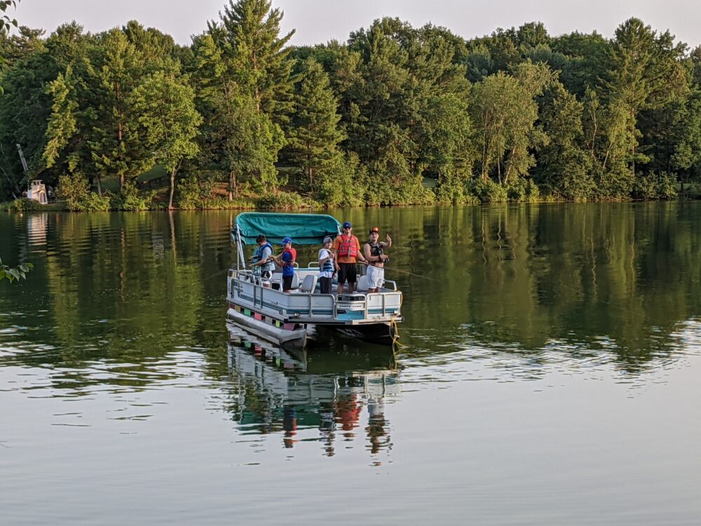 Photo of a group of people fishing off of a pontoon boat
