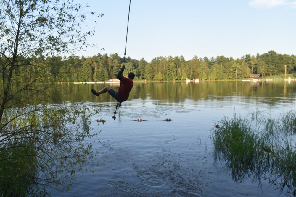 Photo of a person swinging from a rope swing into Lions Lake