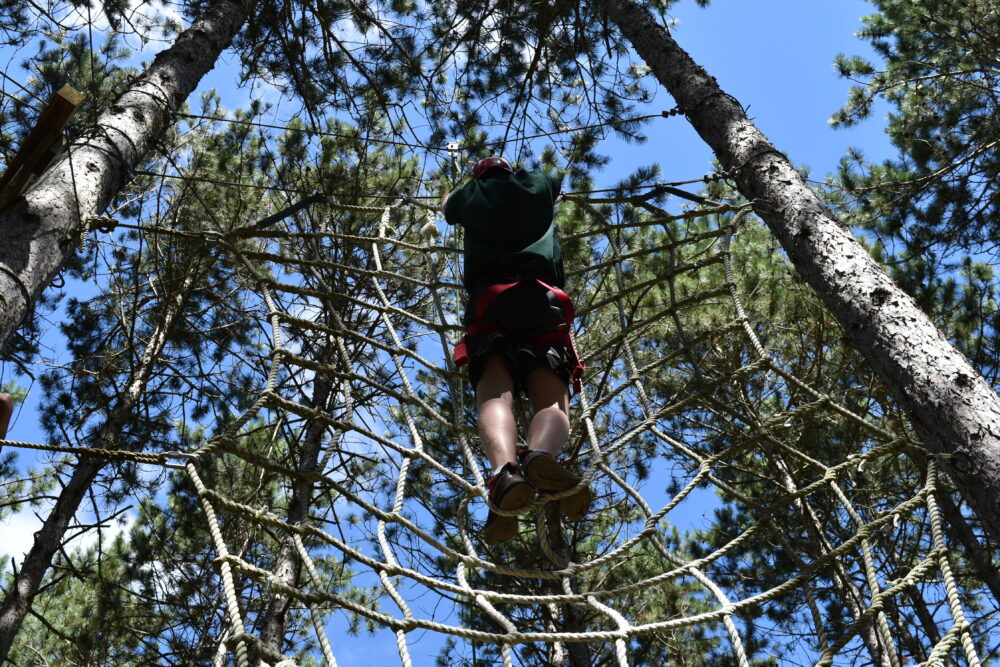 A photo of a person climbing the cargo net in the woods