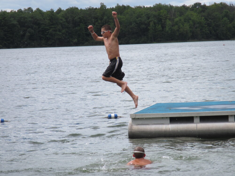Photo of a child jumping off of a raft into Lions Lake