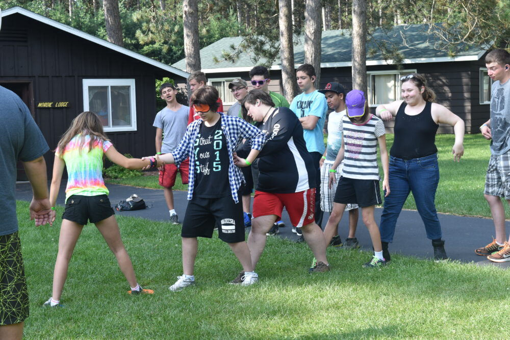 Photo of a group team building activity where one person is blindfolded and other people are holding on and helping them