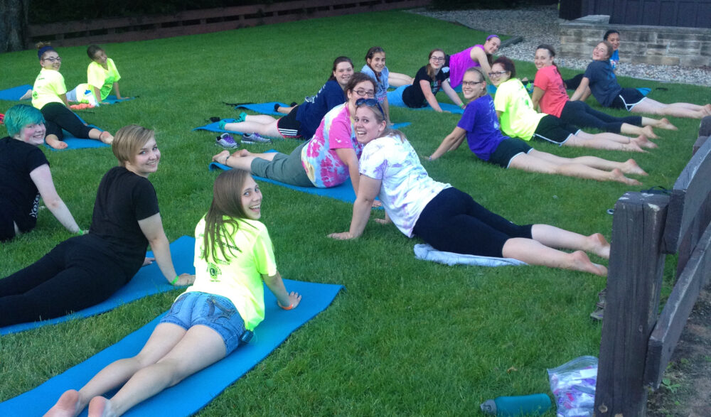 Photo of group smiling at the camera while doing yoga